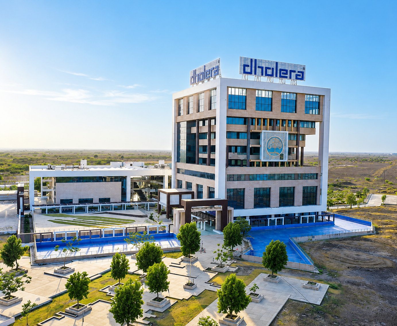 Aerial view of the Dholera administrative headquarters building with blue water features, landscaped plazas and open surrounding land